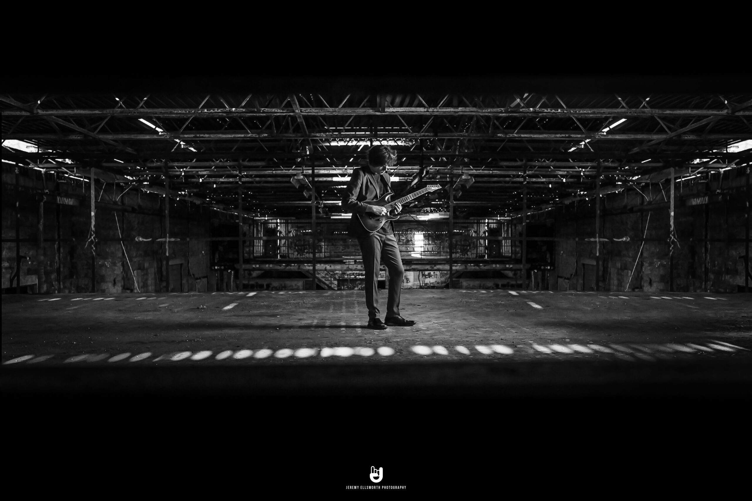 High school senior boy playing guitar in an abandoned warehouse, captured by a Kansas City senior photographer for a unique and artistic portrait session