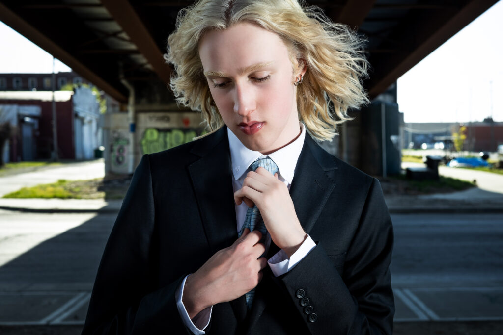 High school senior boy in a suit and tie standing in the West Bottoms of Kansas City, captured by a Kansas City senior photographer for a sophisticated urban portrait session